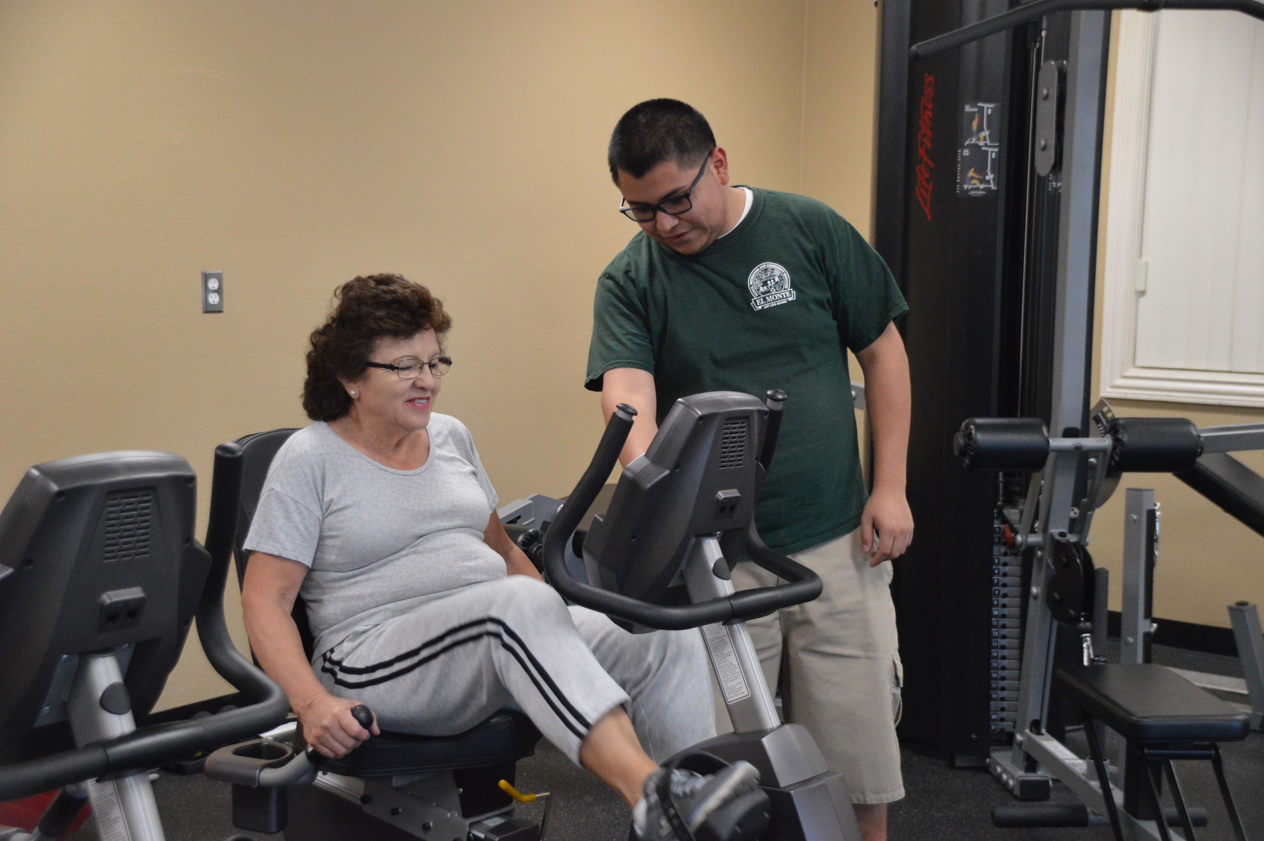Staff assisting woman on the machine at the senior gym