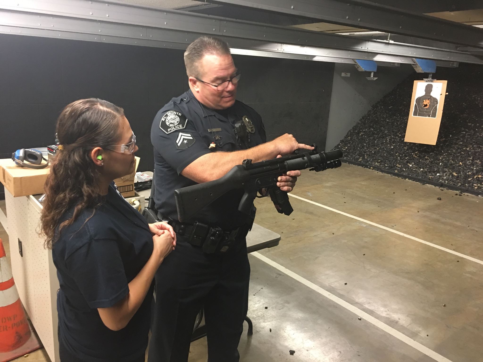 Officer Showing Woman a Part of a Gun at Shooting Target Space
